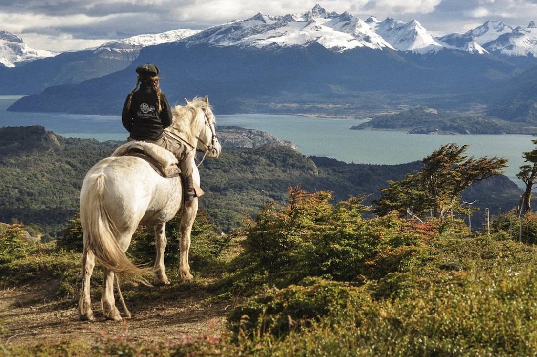Jinete a caballo frente a fiordos y cumbres nevadas, Proyecto de Conservación La Península, Magallanes